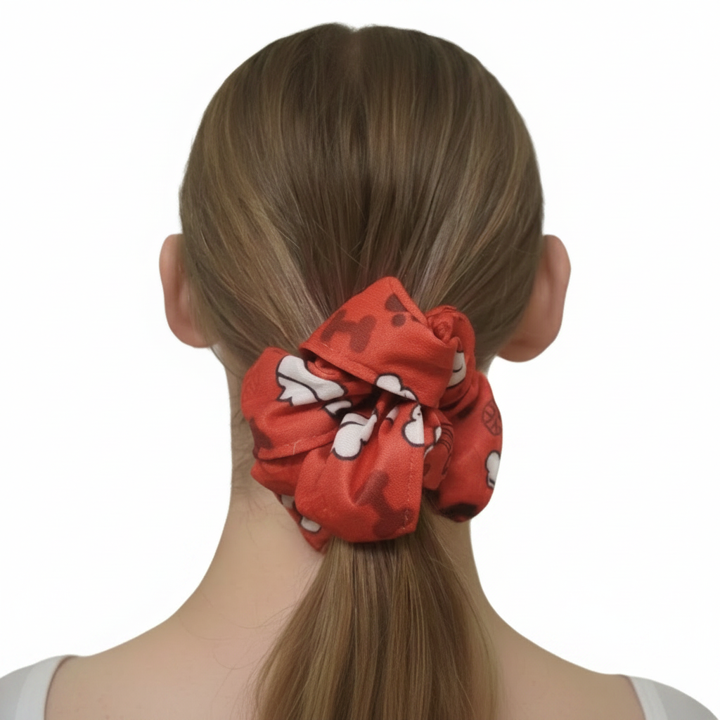 Waterproof red fabric hair scrunchie with white dog paw and bone pattern, one size fits all pet-themed hair accessory shown in a ponytail.